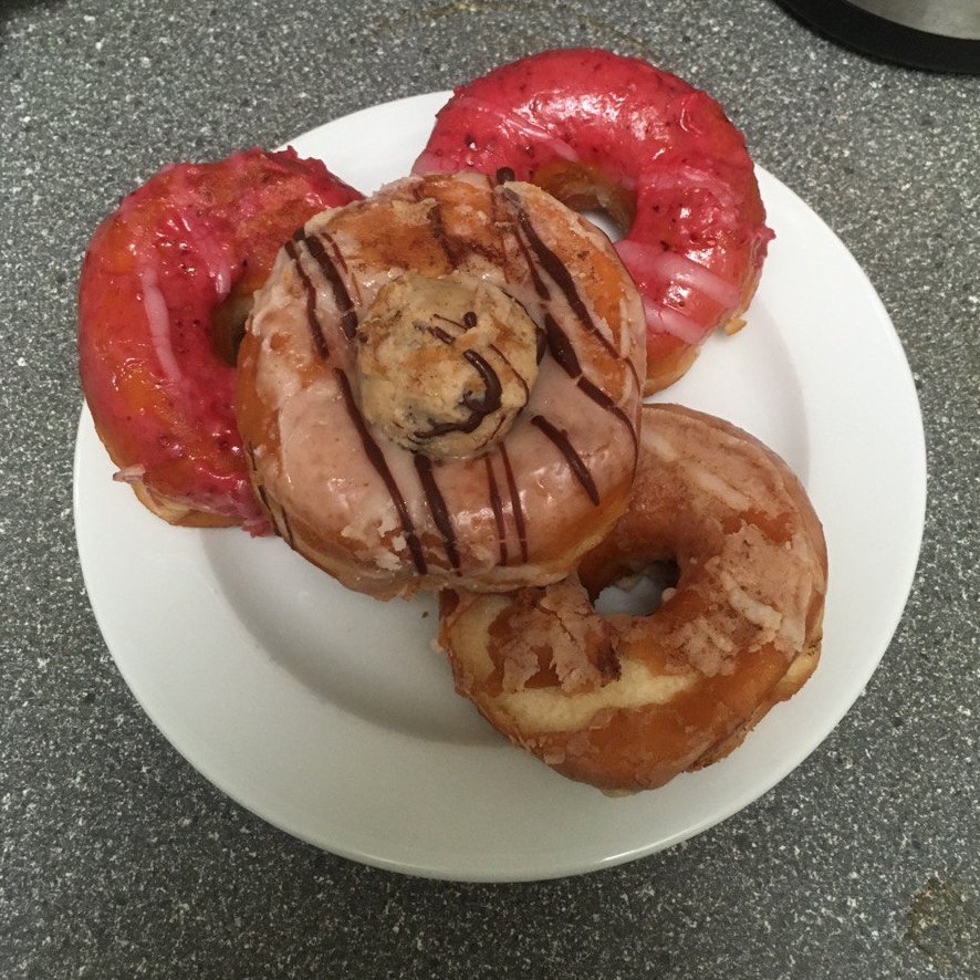 ein weißer Teller mit vier Donuts